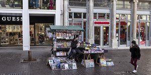 Γυναίκα περνά από περίπτερο με εφημερίδες