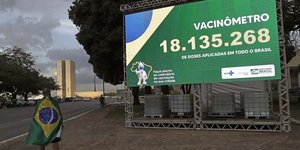 Πολίτης κοιτάζει πίνακα με αριθμό εμβολιασμένων στην Βραζιλία