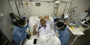 Ασθενής στο κρεβάτι μιλάει με υγειονομικούς