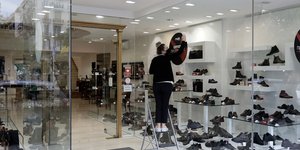 Υπάλληλος φροντίζει βιτρίνα σε μαγαζί με παπούτσια