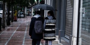 Νεαροί περπατούν με ομπρέλα
