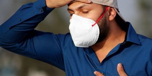 Άνδρας με μπλε πουκάμισο και μάσκα κρατά την καρδιά του