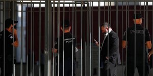 Ο Γιάννης Λαγός κοιτάζει το κινητό του μπροστά σε αστυνομικούς