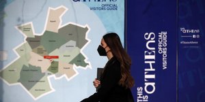 Γυναίκα περπατά με φόντο τουριστικό χάρτη της Αθήνας