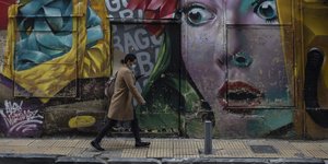 Γυναίκα περπατά δίπλα από γκράφιτι