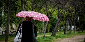 Γυναίκα περπατά με ομπρέλα σε πάρκο