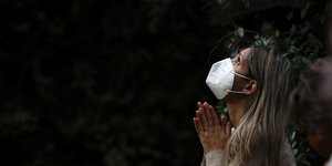 Γυναίκα προσεύχεται φορώντας μάσκα