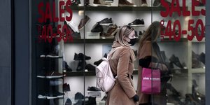 Γυναίκα περπατά έξω από κατάστημα με παπούτσια