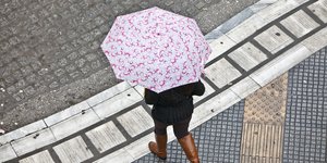 Μια γυναίκα περπατά με ομπρέλα στη βροχή