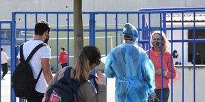 Καθηγήτρια μιλά με υγειονομικό σε είσοδο σχολείου