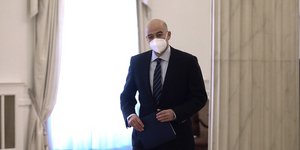 Ο Νίκος Δένδιας περπατά κρατώντας φάκελο
