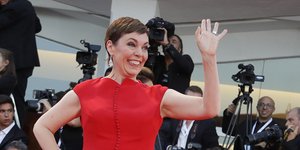 Η Ολίβια Κόλμαν με κόκκινο φόρεμα χαιρετά