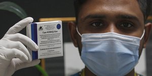 Ανδρας κρατά το εμβόλιο της Ρωσίας κατά του κορωνοϊού