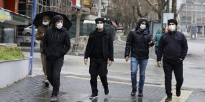 Τούρκοι με μάσκες περπατούν στη βροχή