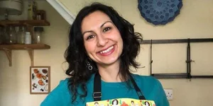 Η συγγραφέας βιβλίων μαγειρικής Γιασμίν Καν με χρωματιστή ποδιά χαμογελά