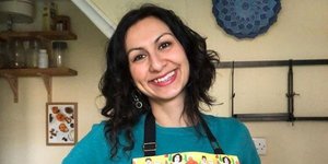 Η συγγραφέας βιβλίων μαγειρικής Γιασμίν Καν με χρωματιστή ποδιά χαμογελά
