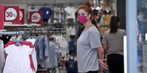 Υπάλληλος σε κατάστημα ρούχων με μπλούζα και ρούχα στα ράφια
