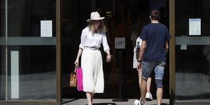 γυναίκα με λευκή φούστα βγαίνει από μαγαζί στην Τσεχία άνδρας με τζιν βερμούδα μπαίνει