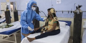 γυναίκα ασθενής σε κρεβάτι νοσοκομείου με νοσοκόμα δίπλα της στην Ινδία