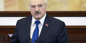 Αλεξαντερ Λουκασένκο με γραβάτα και κοστούμι σε έδρανα με μικρόφωνα