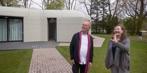 To ζευγάρι των Ολλανδών ενοίκων μπροστά στο νέο τους κατασκευασμένο από 3D εκτυπωτή σπίτι 