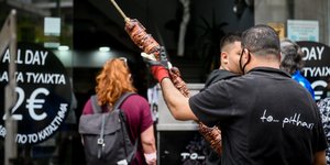 άνδρας με κοκορέτσι έξω από μαγαζί για Κυριακή του Πάσχα