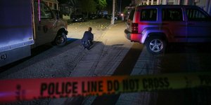 Αστυνομικός σκυμμένος κάνει έρευνα ανάμεσα σε αυτοκίνητα σε δρόμο στο Ρουντ Αϊλαντ, όπου έγινε ανταλλαγή πυρών