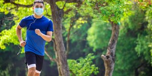 Άνδρας με μπλε μπλούζα κάνει τζόκινγκ φορώντας μάσκα