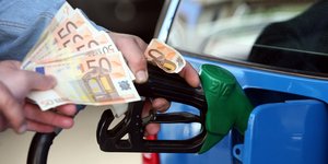 Υπάλληλος πρατηρίου καυσίμων βάζει βενζίνη σε αυτοκίνητο κρατώντας ευρώ στο χέρι