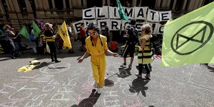 γυναίκα με κίτρινη φόρμα σε διαδήλωση για κλιματική αλλαγή στην Αυστραλία