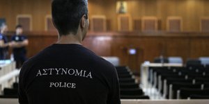 αστυνομικός με γυρισμένη πλάτη σε αίθουσα σε δικαστήριο