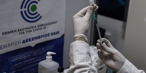 εμβόλιο σε χέρια γιατρού σε εμβολιαστικό κέντρο