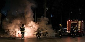 Πυροσβέστες δίπλα σε πυροσβεστικό όχημα σβήνουν φωτιά σε αυτοκίνητο