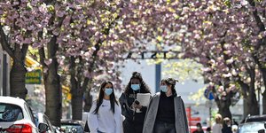 γυναίκες με μάσκες περπατούν στη Γερμανία κάτω από ανθισμένες κερασιές