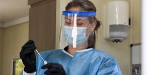 Γυναίκα γιατρός με rapid test στο χέρι μάσκα