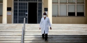 γυναίκα με στολή και μάσκα έξω από Σισμανόγλειο στα σκαλιά