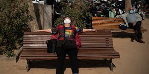 Γυναίκα κάθεται με μάσκα σε παγκάκι στην Ισπανία