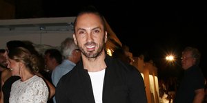 Ιωάννης Μελισσανίδης χαμογελάει στον φακό φορώντας μαύρο σακάκι και λευκή μπλούζα