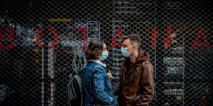 κορίτσι και αγόρι έξω από μαγαζί με κατεβασμένα ρολά
