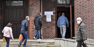 κόσμος με μάσκες ανεβαίνει σκαλιά και μπαίνει σε κτίριο στη Γερμανία