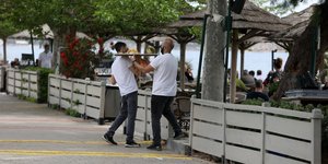 άνδρες σερβιτόροι με δίσκο στα χέρια σε μαγαζί με κόσμο