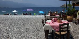 Μαγαζί με τραπεζάκια σε παραλία με λουόμενους