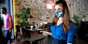 Σερβιτόρα σε καφέ με την μάσκα της και τον δίσκο ανά χείρας