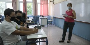 Μαθητές με μάσκες σε αίθουσα διδασκαλίας σχολείου με καθηγήτρια μπροστά στον πίνακα