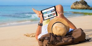 Ανδρας στην παραλία παρακολουθεί το tablet του