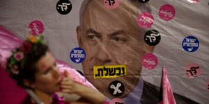 διαδηλώτρια μπροστά από αφίσα με τον Μπέντζαμιν Νετανιάχου