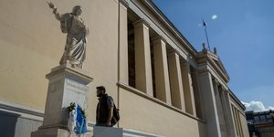 άνδρας κοντά σε άγαλμα έξω από κτίριο Πρυτανείας ΕΚΠΑ 
