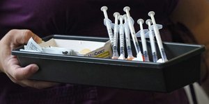 εμβόλια με συσκευασία κρατά γυναίκα με μωβ μπλούζα