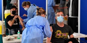 Ανδρες εμβολιάζονται κατά της Covid-19 στη Γερμανία