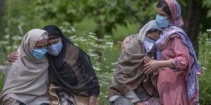 γυναίκες αγκαλιασμένες κάθονται σε πεζούλι στην Ινδία